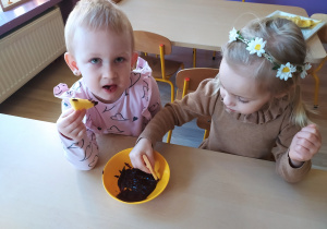 Dzieci moczą owoce w rozpuszczonej czekoladzie